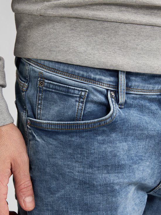 Close-up van de voorkant van een lichtblauwe jeans, met de rechterzak zichtbaar.
