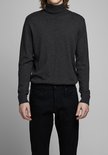 Man in een donkergrijs coltrui en zwarte jeans.
