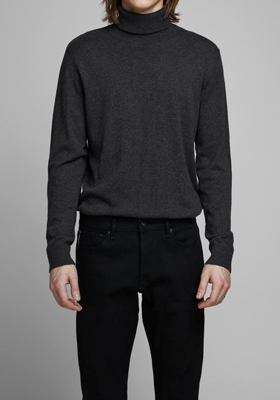 Man in een donkergrijs coltrui en zwarte jeans.