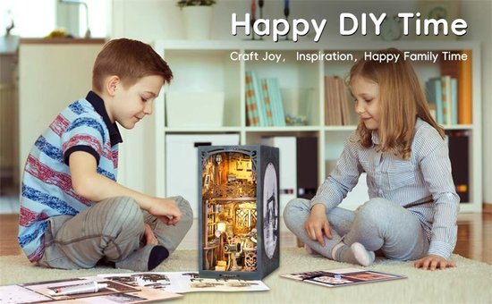 Kinderen bouwen aan een miniatuur filmstudio diorama, zittend op de grond.