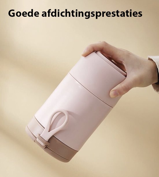 Een hand houdt een roze lunchpot met een lus aan het deksel schuin omhoog.