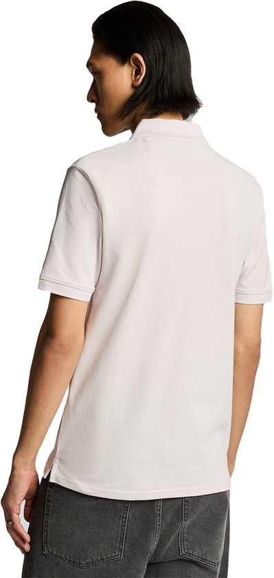 Man met lichtroze poloshirt, achterkant zichtbaar, grijze jeans.