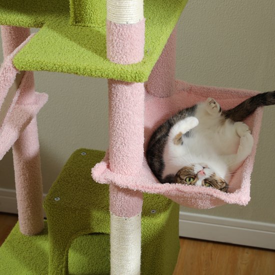 Gestreepte kat ligt ontspannen in de roze hangmand van een groene en roze krabpaal.