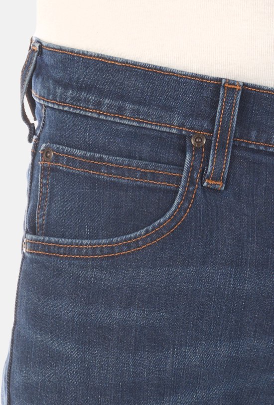 Detail van de zak van een donkerblauwe jeans met oranje stiksels.