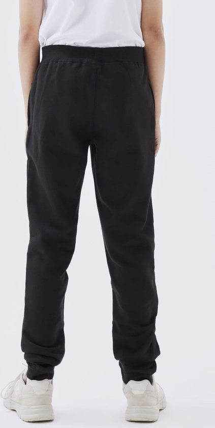 Achterkant van een jongen in een zwarte joggingbroek.
