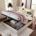 Lit rembourré beige avec espace de rangement relevable rempli de couvertures. Éclairage LED et ports USB dans la tête de lit.