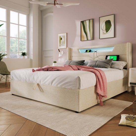 Lit rembourré beige avec éclairage LED dans la tête de lit, espace de rangement sous le matelas. Drapé d'un plaid rose.