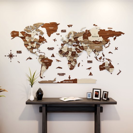 Carte du monde 3D en bois sur un mur avec des avions et des créatures marines, au-dessus d'une console avec des cadres photo et un livre.