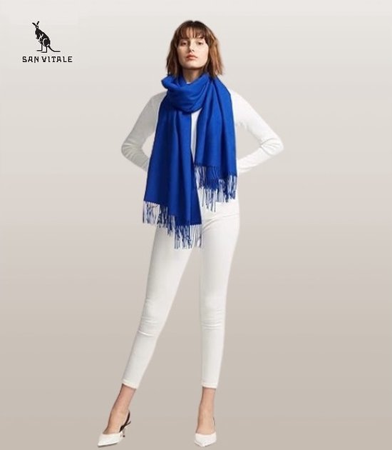 Model met koningsblauwe pashminasjaal met franjes, gedragen met een witte coltrui en witte broek.