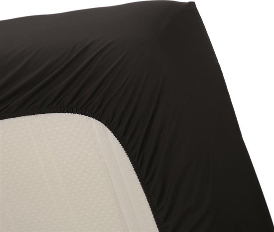 Detail van een zwart hoeslaken dat op een matras wordt aangebracht.
