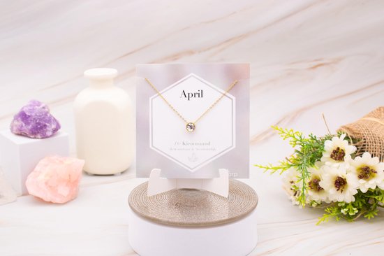 Gouden ketting met een heldere zirkonia hanger, op een kaart met 'April' en de tekst 'De Kiemmaand'.