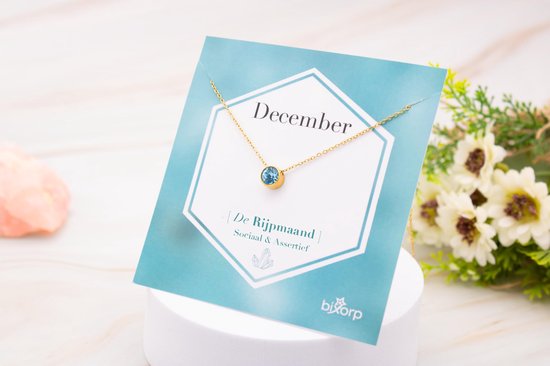 Gouden ketting met blauwe zirkonia op kaart met "December" en "De Rijpmaand".