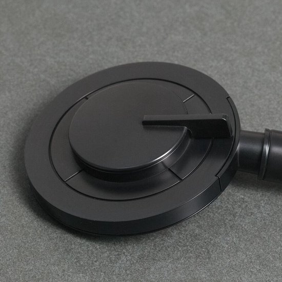 Close-up van een matzwarte, ronde douchekop met een draaiknop en concentrische cirkels.