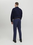 Man van achteren gezien, draagt een donkerblauw overhemd met lange mouwen, een bruine riem en een marineblauwe broek.
