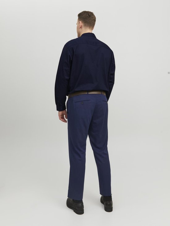Man van achteren gezien, draagt een donkerblauw overhemd met lange mouwen, een bruine riem en een marineblauwe broek.