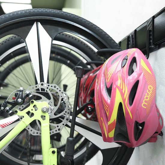 Roze fietshelm met gele strepen naast wielen van racefietsen aan een zwarte muurbeugel.