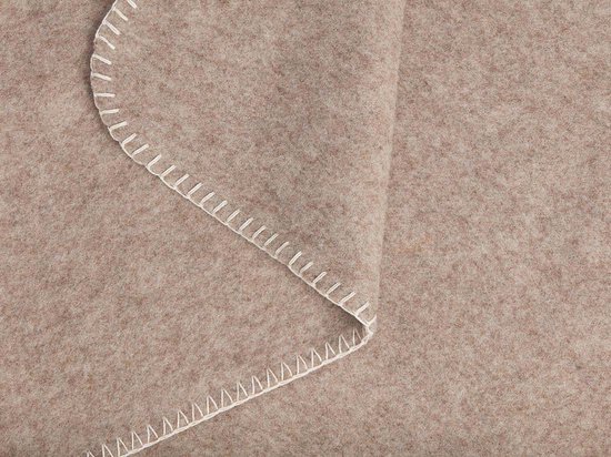 Detail van een beige wollen babydeken met witte zigzagg Stitch.
