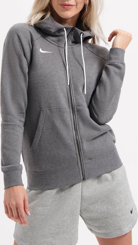 Grijze Nike hoodie met rits, capuchon en witte trekkoordjes, met Nike logo op de borst. De vrouw draagt een short.