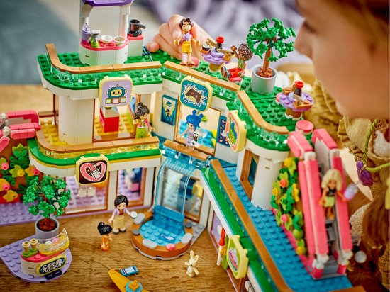 Centre commercial LEGO Friends avec cinq figurines, dont une fille aux cheveux bleus, avec des plantes miniatures, des jeux d'eau et un toboggan.