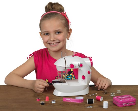Lachend meisje met een roze strik in haar haar, zittend aan een tafel met een witte kindernaaimachine.