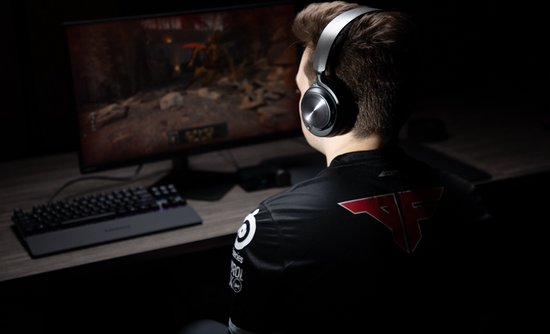 Man met Faze Clan shirt speelt game met Steelseries Arctis Nova Pro headset.