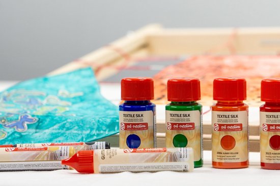 Rij van flessen textielverf: blauw, groen, oranje en rood. Ook tubes met glitterverf.