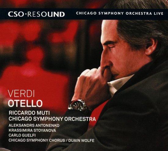 Riccardo Muti, dirigent van het Chicago Symphony Orchestra, in profiel met zijn hand op zijn mond, met rode achtergrond.