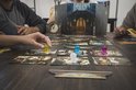 Close-up van Mysterium speelkaarten met pionnen en spelonderdelen op een houten tafel.