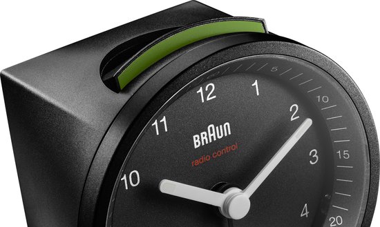 Zwarte wekker van Braun met groene snooze-knop bovenop en analoge wijzerplaat.