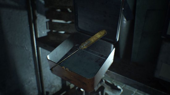 Een metalen medische doos met een gebogen instrument met een gouden handvat.