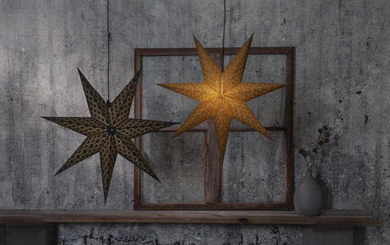 Deux étoiles de Noël en papier, une noire avec des détails dorés et une dorée, suspendues devant un mur gris.