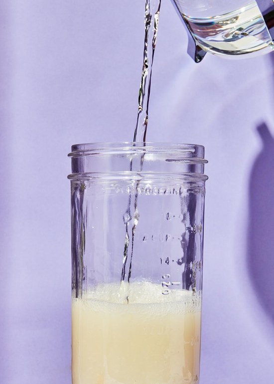 Kristalhelder water wordt in een glazen pot met een laagje schuim gegoten.