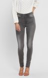 Model draagt een grijze skinny jeans met een witte geborduurde blouse.