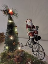 Kerstman op driewieler, op plateau van hout met kerstboom en dennenappeltjes, ledverlichting 30cm diameter