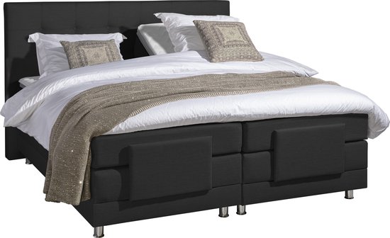 Zwart boxspringbed met gestreept sprei, witte lakens, decoratieve kussens en hoofdbord met knopen.