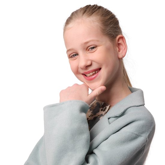 Lachend meisje met blonde paardenstaart, draagt een lichtblauwe jas en een kleine oorring.