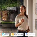 Vrouw in witte blouse en spijkerbroek kijkt naar buiten, slimme verlichting pictogrammen.