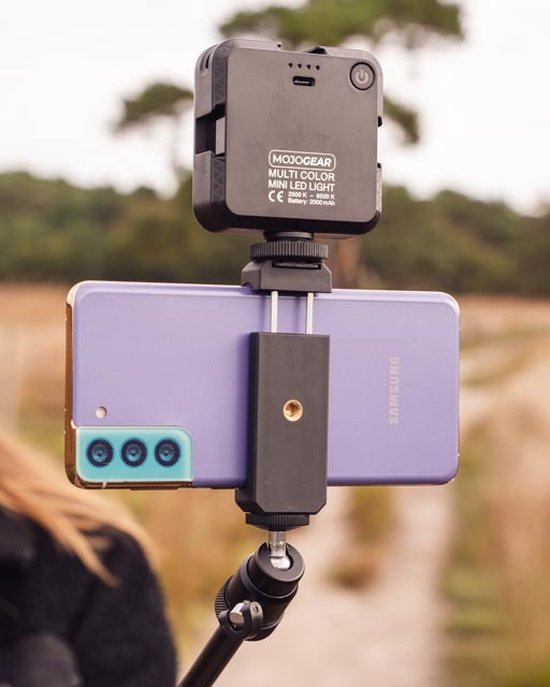 Een paarse Samsung smartphone met MOJOGEAR MULTI COLOR MINI LED LIGHT lamp, bevestigd aan een selfiestick en statief.