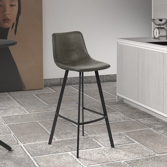 Tabouret de bar gris en similicuir cousu avec pieds noirs dans un intérieur de cuisine.