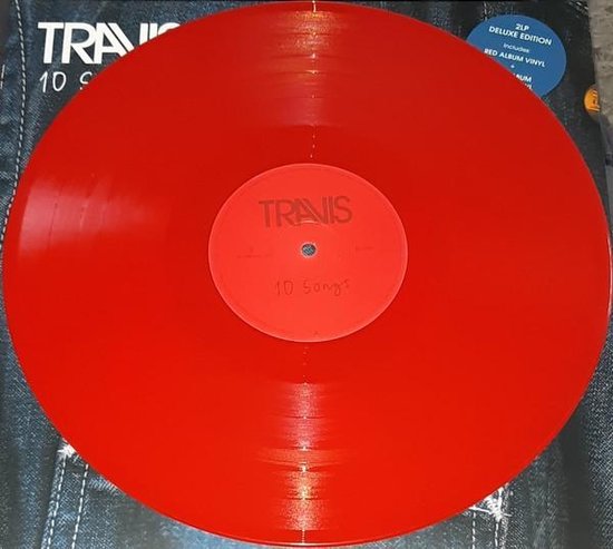 Rood vinyl met het Travis logo en '10 Songs' op de label. De achtergrond is een spijkerbroek.