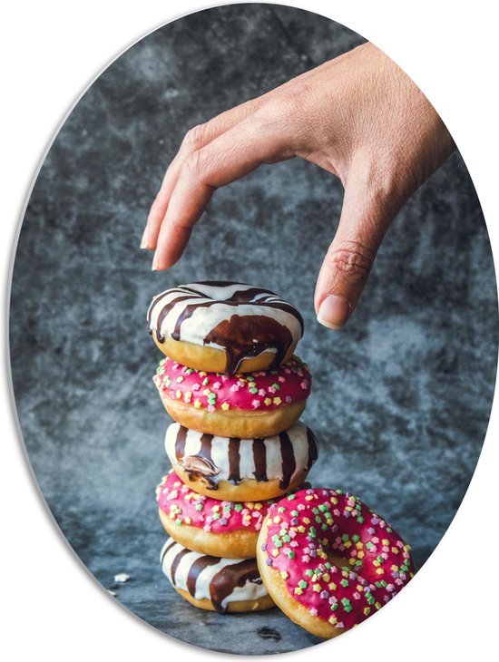 PVC Schuimplaat Ovaal - Donuts - Gestapeld - Sprinkels - Hand - Kleurrijk - 51x68 cm Foto op Ovaal (Met Ophangsysteem)