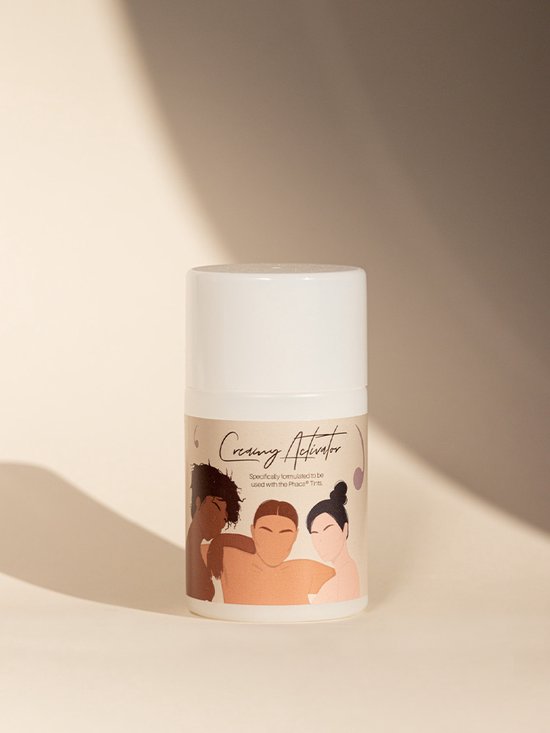 Een witte fles met de tekst "Creamy Activator" en een illustratie van drie vrouwen met verschillende huidskleuren.