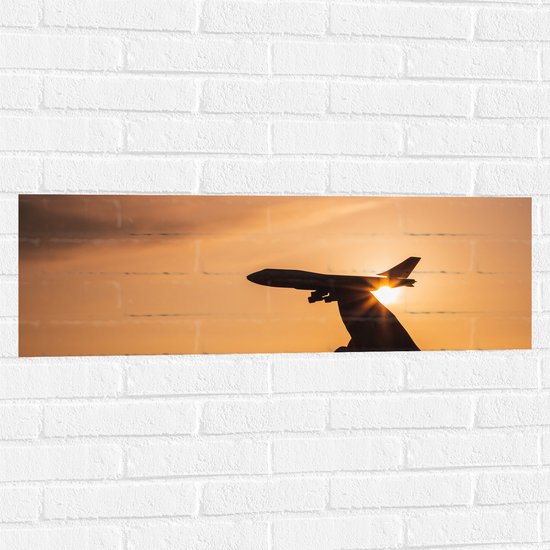 Muursticker - Speelgoed Vliegtuig in Mensenhand bij Zonsondergang - 90x30 cm Foto op Muursticker