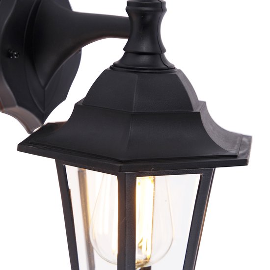 Detail van de zwarte wandlamp met glazen panelen en zichtbare gloeilamp.