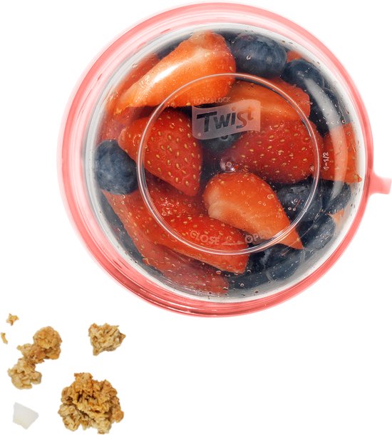 Bocal rempli de yaourt, muesli et morceaux de fruits, avec un couvercle ouvert à côté.