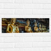 Muursticker - Rijen Gouden Boeddha's in Wat Tham Khuha Sawan Tempel in Thailand - 60x20 cm Foto op Muursticker