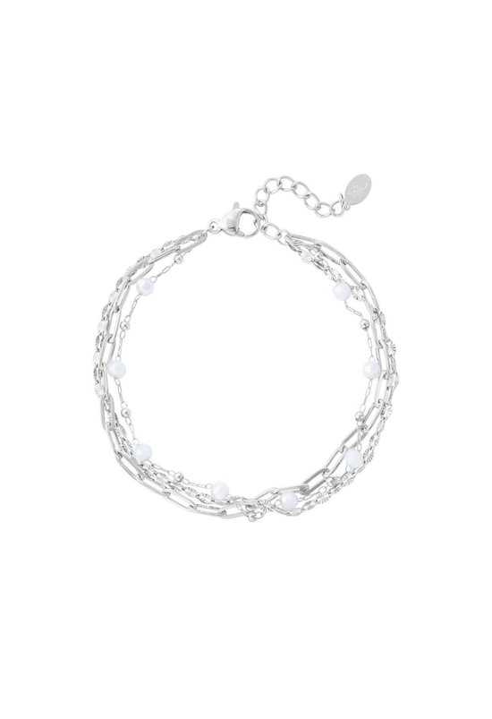 Zilverkleurige armband met vier dunne schakelkettingen en witte pareltjes.