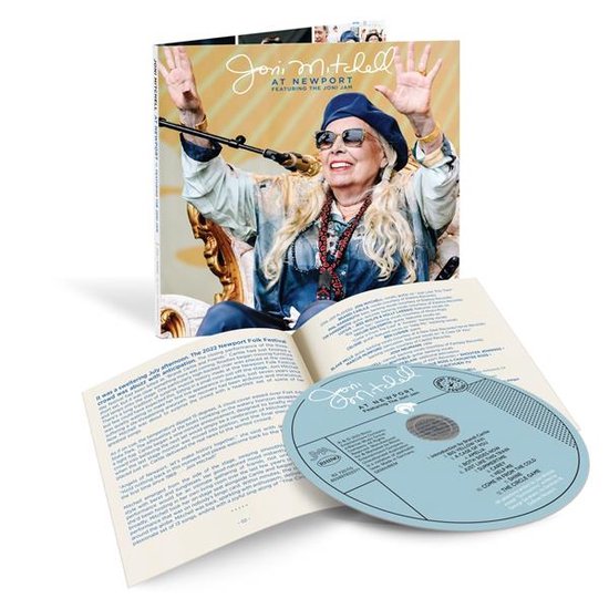 Couverture de CD avec Joni Mitchell, mains levées, assise sur une chaise, portant un béret bleu et des lunettes. Boîtier de CD ouvert avec le CD.
