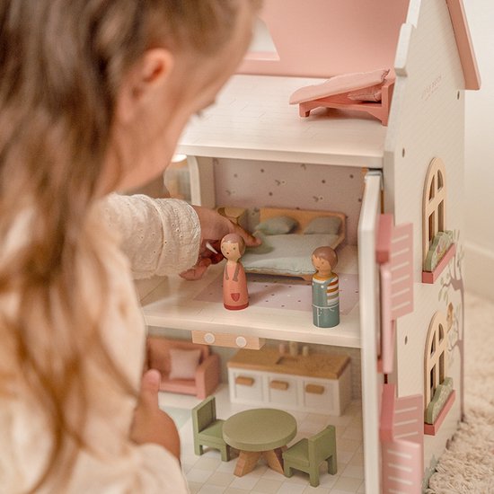 Meisje met een staart speelt met de poppetjes in een open houten poppenhuis.