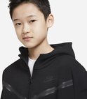 Jongen in een zwart Nike Tech Fleece vest met capuchon, deels open geritst.